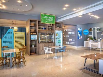 Moderne, lichte hotel-lobby met zitgedeeltes, wachtruimte en decoratieve houten details.