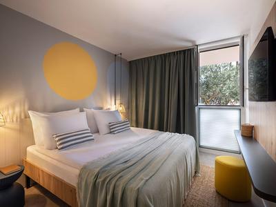 Modern hotelkamer met tweepersoonsbed, groot raam en stijlvolle verlichting.