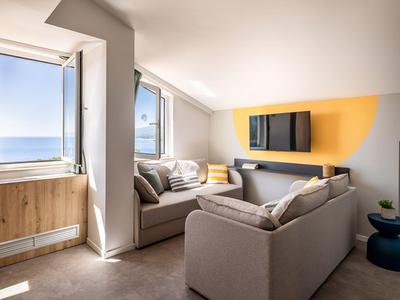 Gezellige hotelkamer met banken, raam met uitzicht op zee en modern wandontwerp.