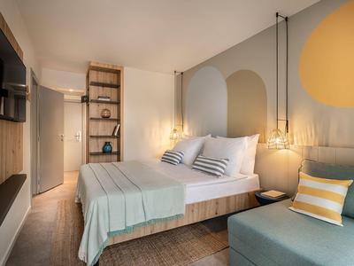 Moderne hotelkamer met tweepersoonsbed, zachte kleuren en een gezellige zithoek.