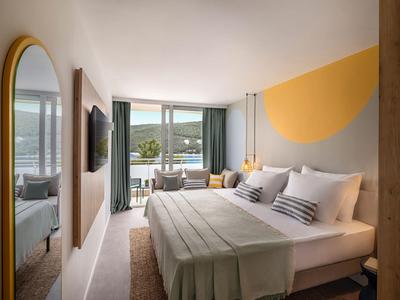 Modern hotelkamer met tweepersoonsbed, zithoek en balkon met uitzicht op zee.
