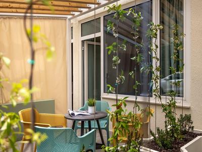 Gezellig hotelbalkon met tafel, stoelen en planten in natuurlijk licht.