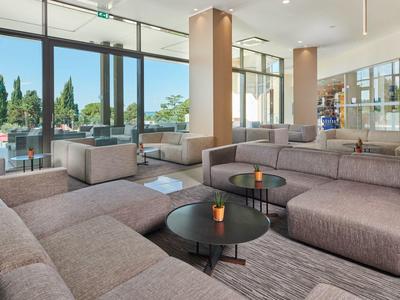 Modernly furnished hotel lounge area with large windows and gray sofas.