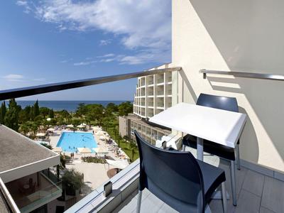 Balcony with desk and chair overlooking pool and sea in the background.