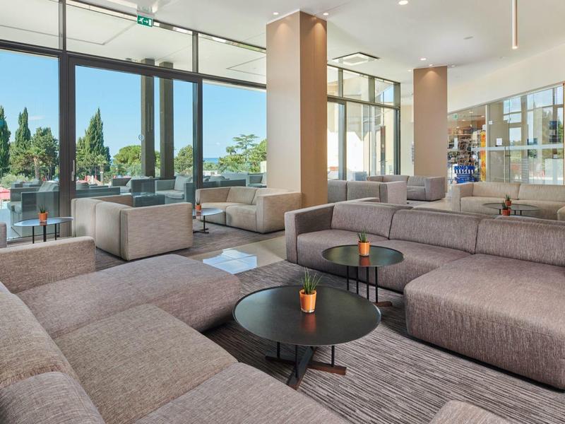 Modernly furnished hotel lounge area with large windows and gray sofas.