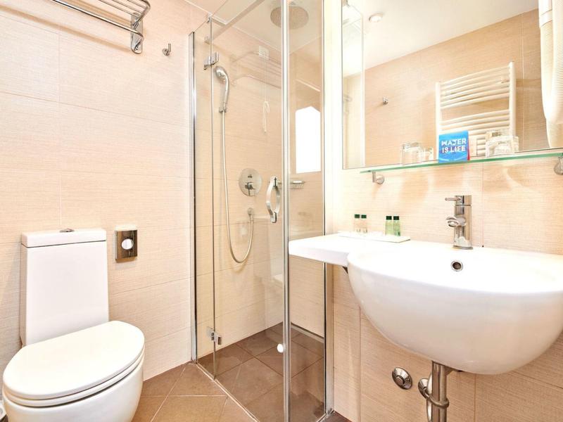 Compact bathroom with shower, toilet, and large mirror.