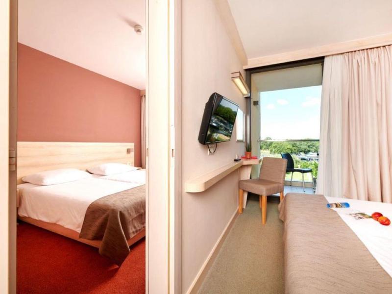 Bright hotel room with balcony and green view.