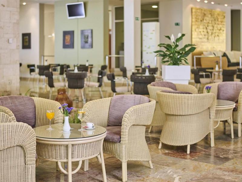 Espace salon élégant d'hôtel avec fauteuils confortables et tables sur sol en marbre.