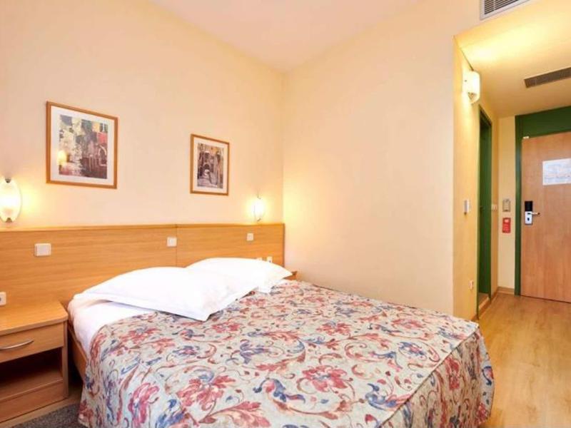 Chambre d'hôtel lumineuse avec lit double et dessus de lit floral.