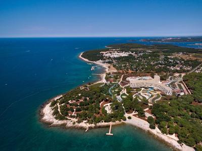 Aerial view of a coastal area with hotel facilities, beaches, and clear blue sea.