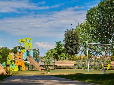 Aire de jeux colorée pour enfants avec balançoires et toboggan sous un ciel bleu dans un parc.
