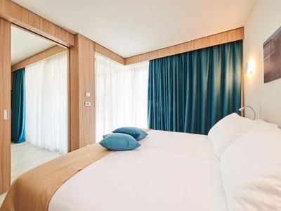 Camera d'hotel luminosa con letto grande e tende blu.