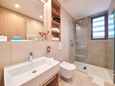 Bagno moderno con vasca, cabina doccia, lavabo e wc in toni neutri.