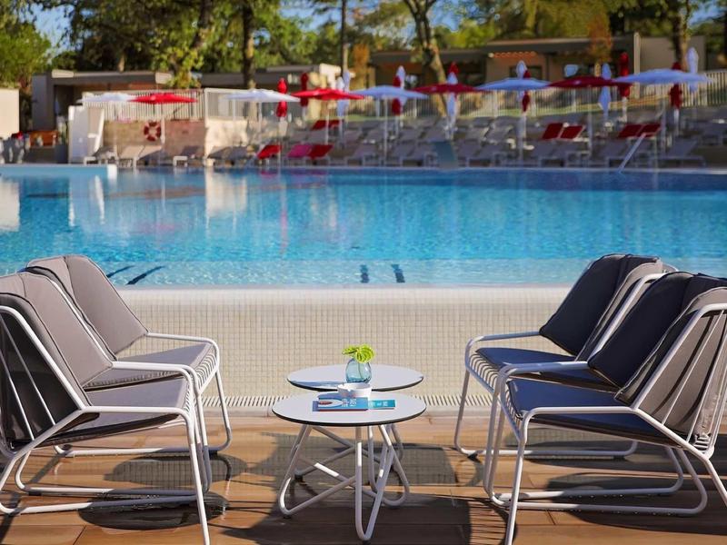 Area salotto moderna con sedie e tavolo vicino a una piscina dell'hotel.