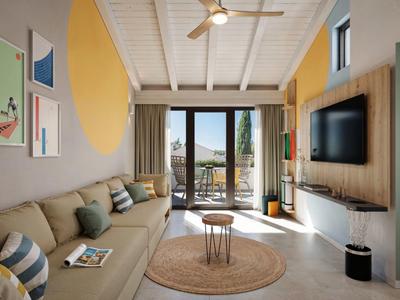 Salon moderne avec canapé clair, grande fenêtre et vue sur terrasse et nature.