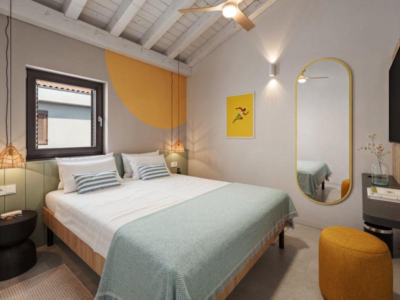 Chambre d'hôtel moderne avec lit double, murs clairs et design minimaliste.