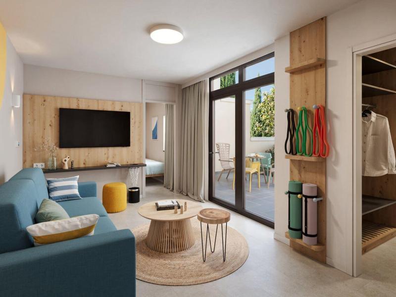 Salon moderne avec canapé bleu, télévision, tables transparentes et accès à la terrasse.