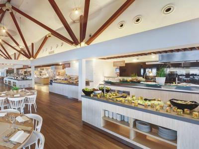 Bright, modern restaurant with wooden ceiling, buffet, and white furniture.