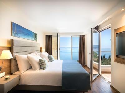 Modern hotel room with double bed and sea view through glass windows and balcony