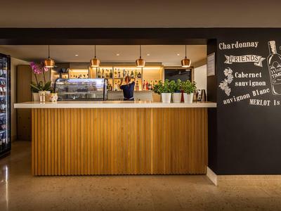 Modern reception area with wooden counter and illuminated wine cooler in the background.