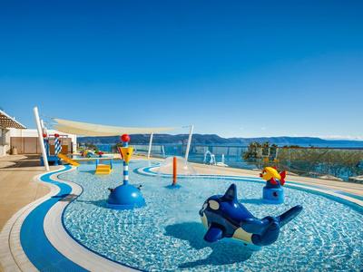 Children's pool with colorful play equipment overlooking the sea and mountains.