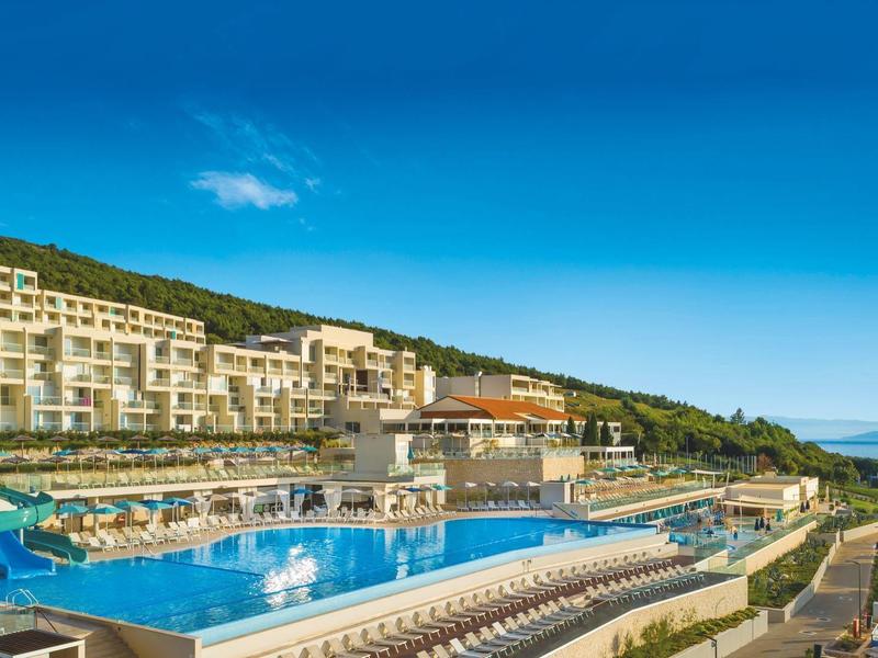 Modern hotel complex with outdoor pool and sun loungers overlooking the sea