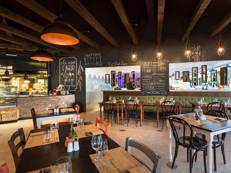 Cozy café with wooden beams, various seating areas, and illuminated boards on the wall.