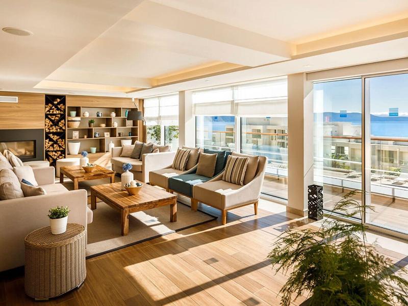 Bright lounge area with comfortable sofas and large windows overlooking the sea.