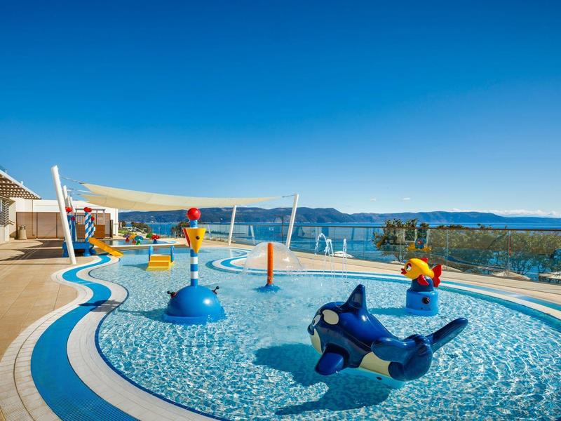 Children's pool with colorful play equipment overlooking the sea and mountains.