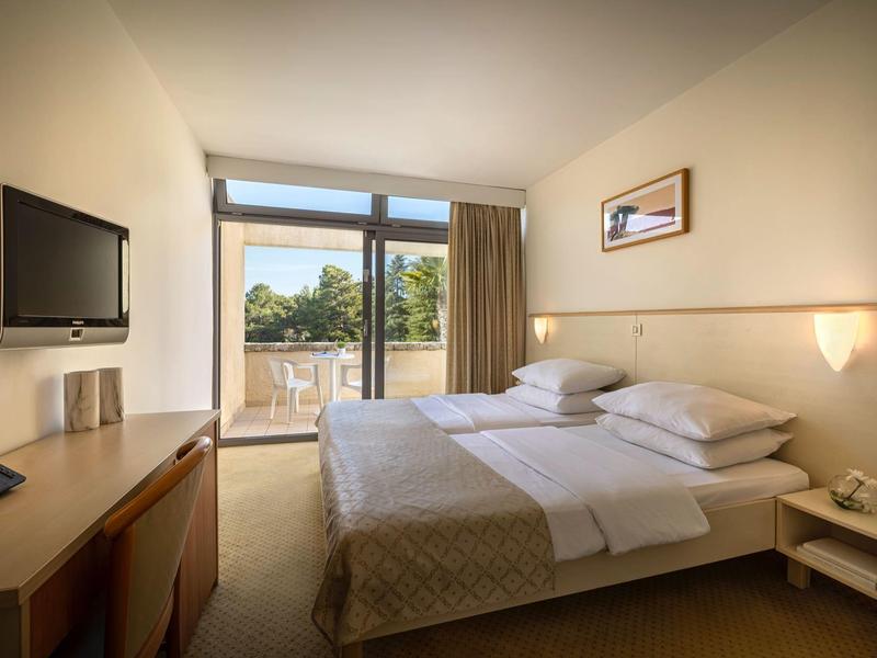 Helles Schlafzimmer mit Doppelbett, Schreibtisch, Balkon und mit Waldblick.