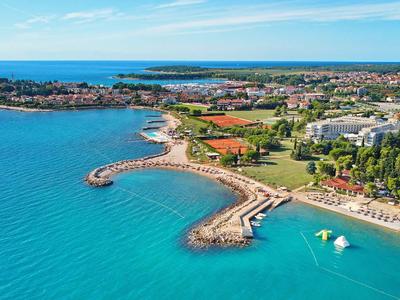 Costa con mare turchese, spiaggia, moli e aree verdi vicino agli hotel.