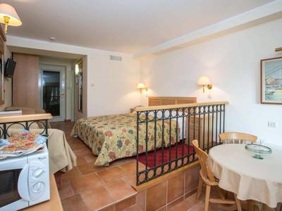 Habitación de hotel acogedora con cama doble, armario, balcón y mesa de comedor con sillas.