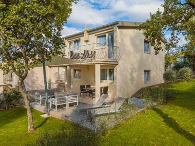 Modern tweeverdiepingenhuis met terras en tuin op een zonnige dag