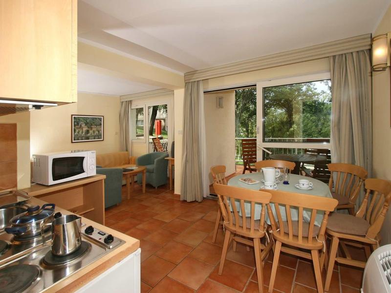 Área de comedor con mesa y sillas de madera junto a gran ventana con vista a jardín verde.