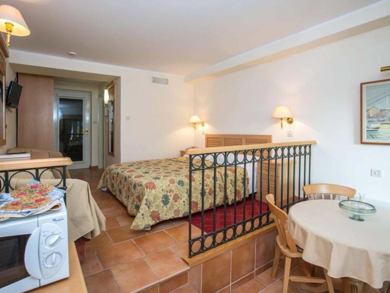 Habitación de hotel acogedora con cama doble, armario, balcón y mesa de comedor con sillas.