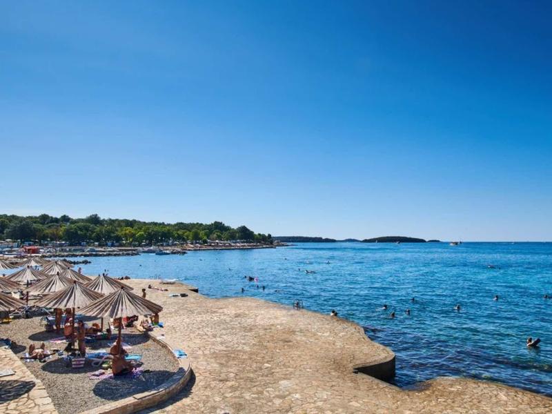 Pequeña zona de playa con sombrillas y agua azul clara en una tranquila costa.