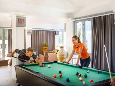 Freundinnen spielen in einem hellen Wohnzimmer Billard und haben Spaß.