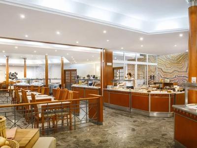 Geräumiger Hotel-Speisesaal mit Holzstühlen, Buffettischen und dekorativen Säulen.