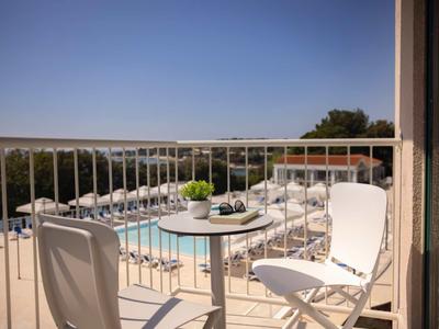 Piccolo balcone con sedie bianche e tavolo con vista su piscina e mare