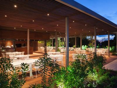Salon extérieur couvert avec mobilier moderne et plantes au crépuscule.