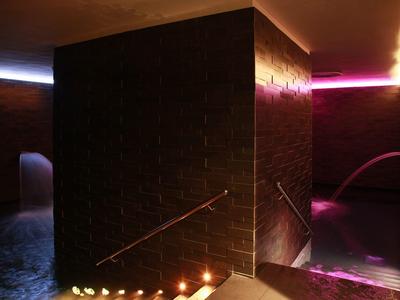 Ciemna strefa spa z świecami, schodami i kolorowym oświetleniem.