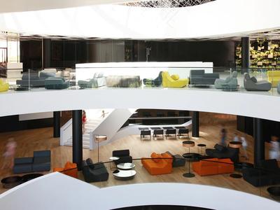 Nowoczesne, otwarte wnętrze hotelu z zakrzywionymi piętrami i kolorowymi miejscami do siedzenia.