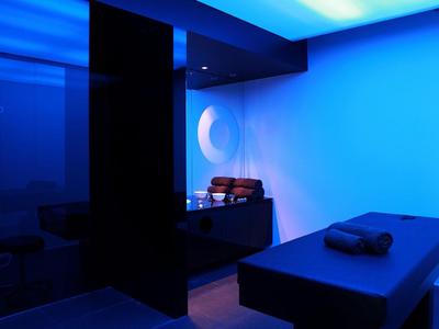 Nowoczesne spa z leżanką do masażu i relaksującym niebieskim oświetleniem.