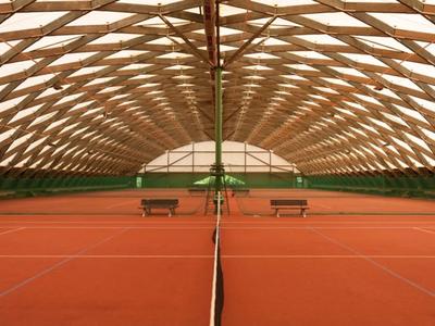 Court de tennis couvert en terre battue avec toit en ossature bois et fenêtres