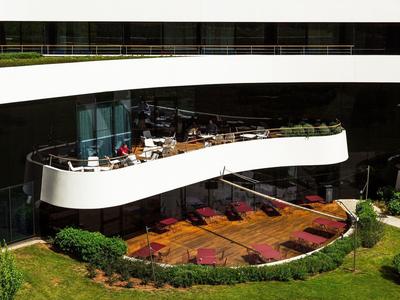 Balkon nowoczesnego hotelu z miejscami do siedzenia i widokiem na zadbany ogród.