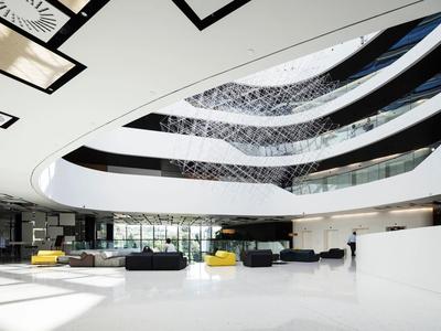 Przestronne nowoczesne lobby hotelowe z białą podłogą, zakrzywionym oknem sufitowym i miejscami do siedzenia.