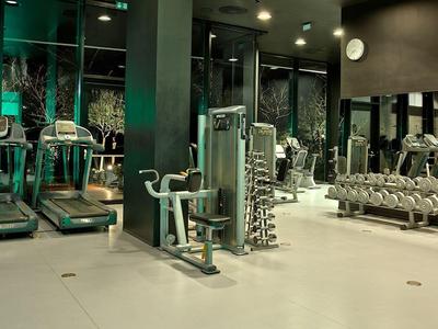 Salle de sport moderne avec plusieurs appareils d'exercice et miroirs sur le mur.