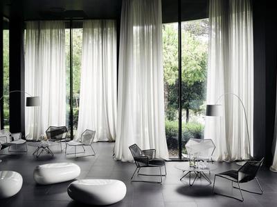 Nowoczesny, minimalistyczny salon z dużymi oknami i białymi zasłonami.