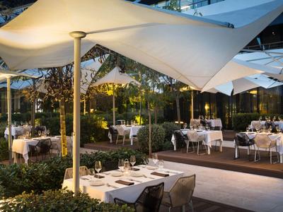 Terrasse de restaurant en soirée avec tables dressées et grands parasols extérieurs.