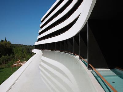Moderne Hotelfassade mit geschwungenen weißen Balkonen und klarem blauen Himmel im Hintergrund